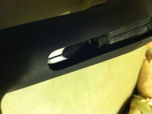 Screws in through the back of the pistol grip and has a rubber cover.